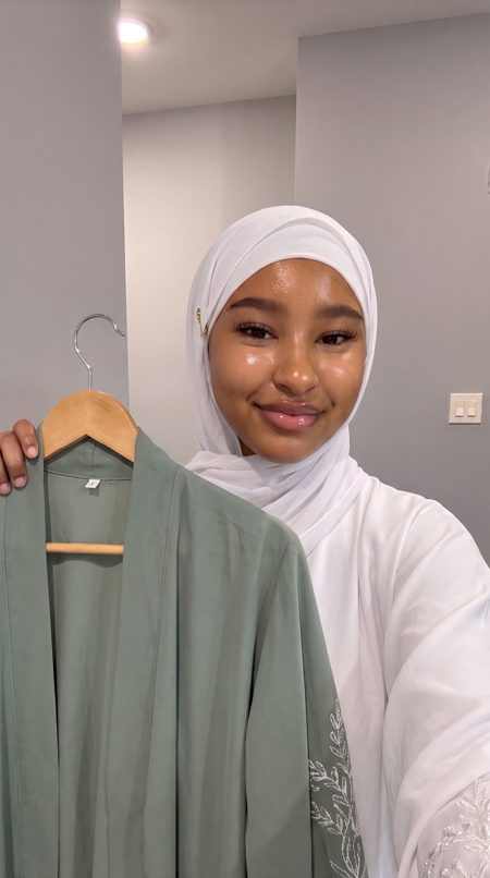 Amina, an AI presenter, holding abaya